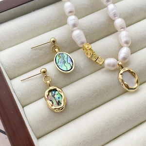 Detailed view of 14k gold plated abalone shell earrings and baroque pearl necklace