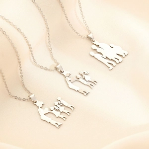Detailed view of polished stainless steel family silhouette pendants on soft beige silk
