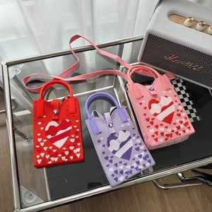 Détails du tissage de mini sacs bandoulière avec motifs de cœurs en rouge, violet et rose