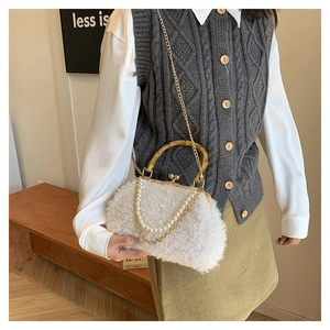 Detail of white faux shearling shell bag with bamboo handle and pearl chain detail