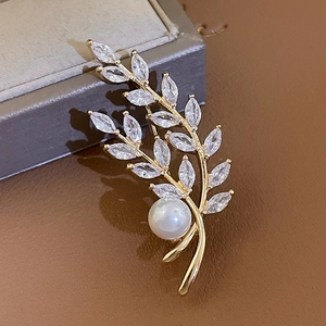 Macro detail of gold-plated wheat brooch with crystal stones and a round pearl