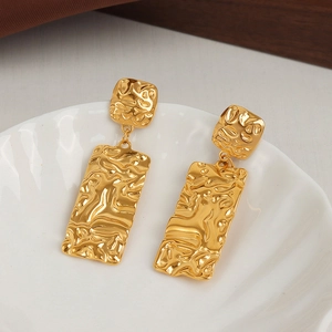 Modern gold-plated square earrings with a hammered texture finish on a white plate