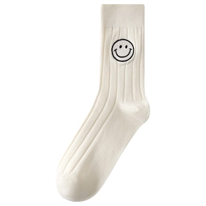 White cotton mid-calf socks with black embroidered smiley face in a minimalist flat lay