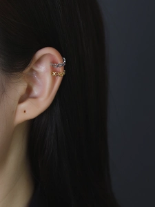 Close-up of heart-shaped ear cuffs in gold and silver finish worn by a model