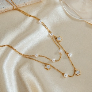 Close-up of a double-layer gold necklace with white shell flowers and pearls on silk