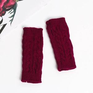 Detail of wine red cable-knit fingerless gloves with soft twisted wool texture