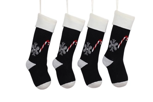 Detailed view of four black knitted Christmas stockings with snowflake and candy cane patterns