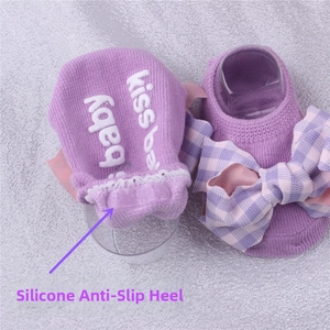 Close-up of baby socks featuring silicone anti-slip heel and decorative purple bow