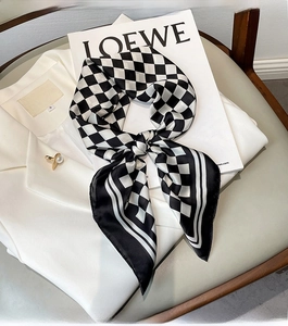Close-up of knotted black and white checkered silk scarf on a white blazer