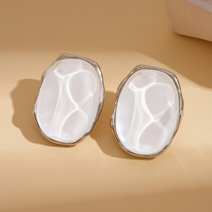 Macro detail of silver geometric oval earrings with white mother-of-pearl texture