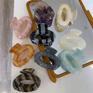 Collection of marble textured acetate hair claws in various colors on a mirror surface