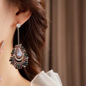 Detailed view of teardrop crystal tassel earrings worn by a model in soft lighting