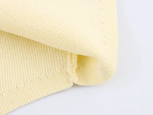 Close-up of pale yellow knit top showing detailed ribbed texture and stitching quality