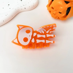 Detail of orange cat skeleton hair claw clip for Halloween on a decorative stone base