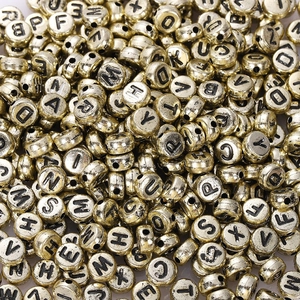 Macro shot of assorted golden acrylic alphabet beads for DIY jewelry making and crafts