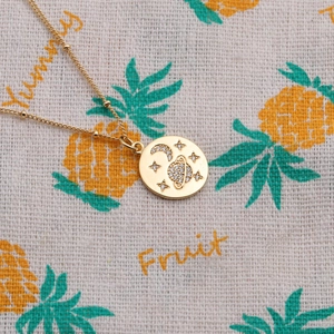Close-up of golden round pendant necklace with zircon moon, star and saturn pattern detail