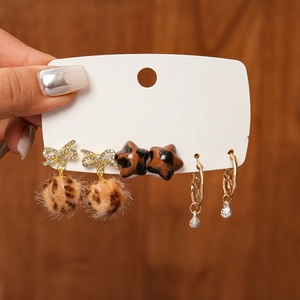 Close-up of 6-piece earring set featuring leopard fur balls and golden stars on card
