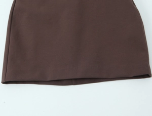 Detailed close-up of dark brown skirt hem showing high-quality stitching and smooth fabric