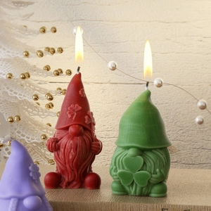 Tres velas de gnomos en rojo verde y púrpura con diseño de trébol sobre madera