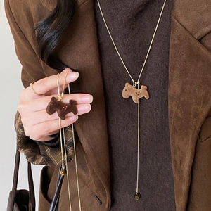 Detailed close-up of brown flocked dog pendant on a gold long chain necklace
