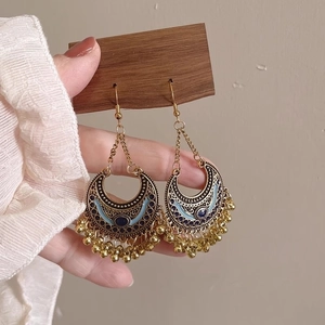 Detail of vintage gold crescent earrings with blue enamel and dangling metal beads