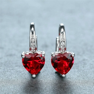 Macro shot of silver earrings with heart-shaped red ruby and sparkling zircon accents