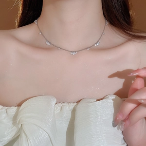 Detail shot of delicate silver necklace with clear zircon pendants on model neck