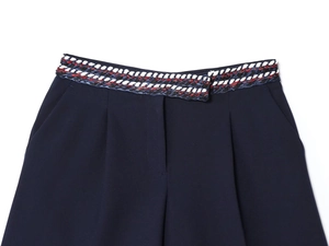 Gros plan du short en sergé bleu marine avec détail de ceinture tressée rouge, blanc et bleu