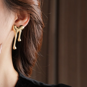 Close-up of molten heart gold earrings on model showcasing liquid metal texture