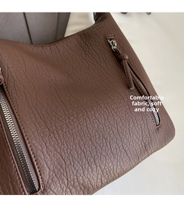 Detail of dark brown leather tote showing soft lychee texture and silver zipper