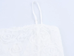 Dettaglio della texture floreale 3D elegante e delle spalline sottili sull'abito bianco