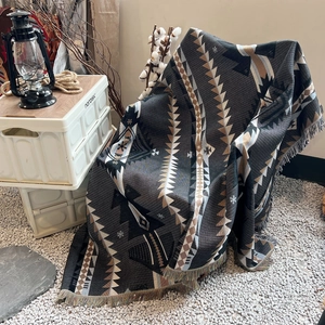 Detail of bohemian geometric knit blanket with tassels in an outdoor camping setup
