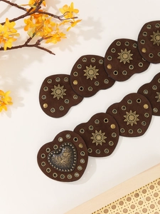 Detail of heart-shaped dark brown suede belt with sunburst studs and floral buckle