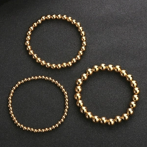 Three beaded gold stainless steel bracelets in different sizes on black background