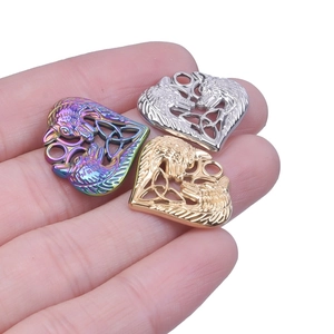 Detailed close-up of heart-shaped double wolf pendants in gold, silver, and rainbow steel