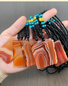 Macro shot of rectangular red agate pendants with natural stripes on a beaded necklace