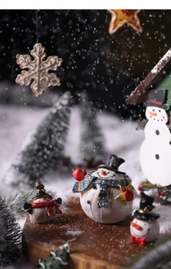 Close-up of resin snowman and snowflake ornaments on a snowy wooden table