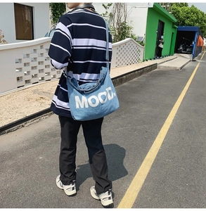 Outdoor shot of a blue denim crossbody bag with large MOOD print worn by a model
