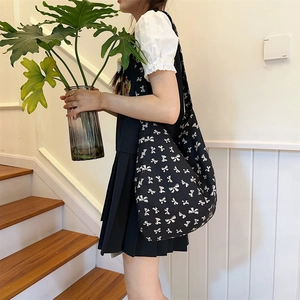 Canvas shoulder bag featuring a stylish black and white bow print pattern in a macro detail