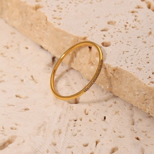 Minimalist 18K gold-plated titanium ring with micro-set zircon on a beige stone surface
