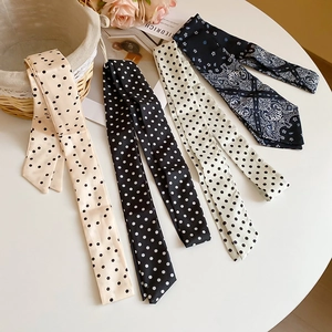 Close-up of elegant polka dot and paisley pattern silk scarves on a white table