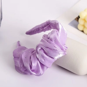 Detailed view of purple satin twisted headband featuring sparkling rhinestone embellishments