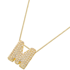 Detailed macro of golden letter M pendant necklace with shimmering cubic zirconia stones