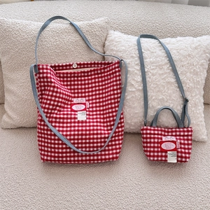 Detail of red and white plaid tweed tote bag set with blue denim straps and logo patch