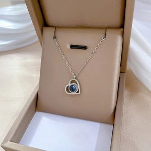 Detail of silver heart necklace with a round blue gemstone inside a jewelry gift box