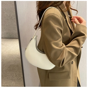 Close-up of white minimalist crescent underarm bag styled with a professional olive blazer