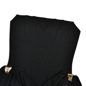 Détail de la robe bustier noire avec tissu plissé et boucles en métal doré élégantes