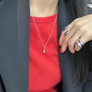 Minimalist 925 sterling silver drop necklace and glossy rings on model in black suit
