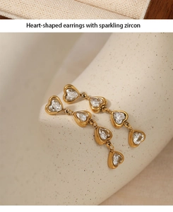 Detailed view of long heart-shaped gold earrings with sparkling zircon on beige fabric