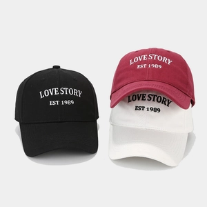 Detailed view of baseball caps in black, white and burgundy with Love Story embroidery